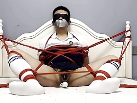 Asian man pleasuring himself with a dildo while being tied up and gagged.