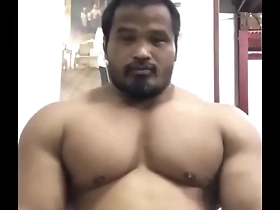 Young Thai hunk showing off his muscles and posing like a bodybuilder.